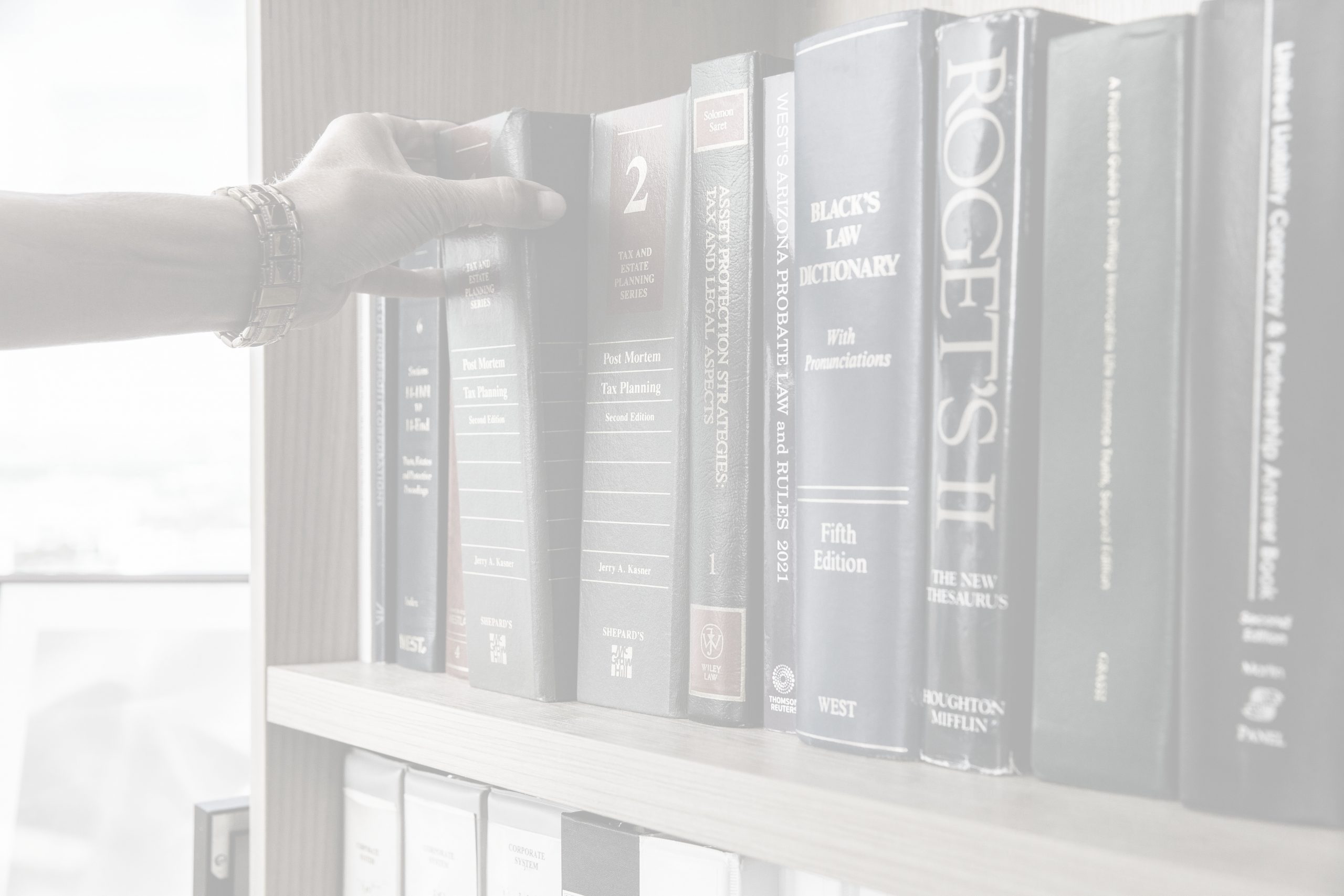 Image of bookshelf with hand pulling one book out.