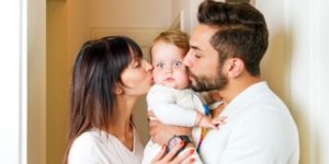 Parents Kissing Child on Cheeks