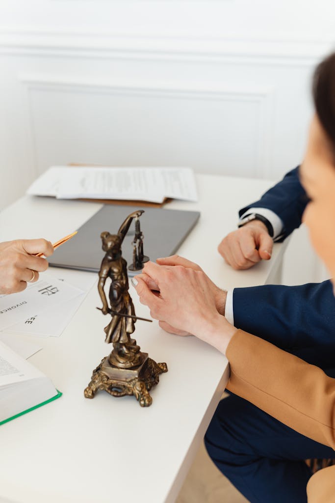 A Couple Holding Hands on a Desk with a Statue of Lady Justice